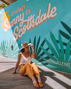 a woman sitting on the ground in front of a sign that says sunny scottdale