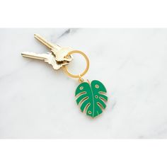 a gold keychain with a green leaf on it and two keys hanging from the front