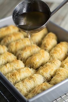 someone pouring sauce on some food in a pan