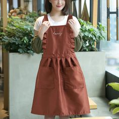 a woman standing in front of a window wearing an apron