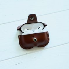 an apple airpods case sitting on top of a white wooden table next to a pair of glasses