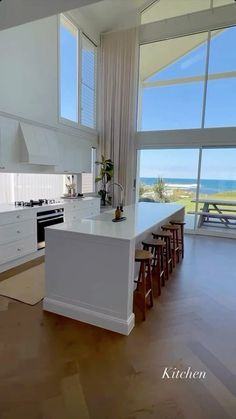 a large kitchen with an island in front of the window overlooking the beach and ocean