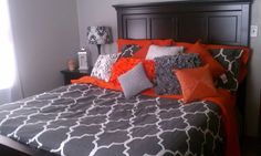 a bed with orange and gray pillows on it