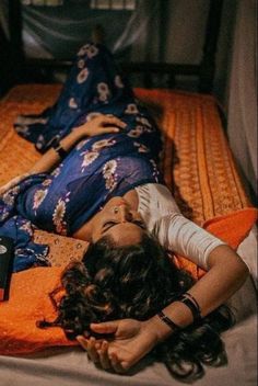 a woman laying on top of a bed with an orange blanket