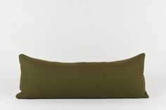 an olive green pillow on a white background