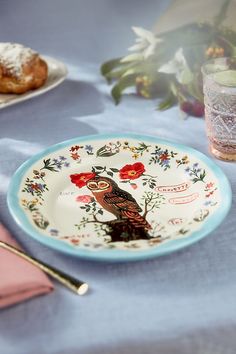 a plate with an owl on it sitting on a table next to other plates and utensils