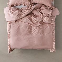 an unmade bed with pink sheets and ruffles on the pillowcase is seen from above