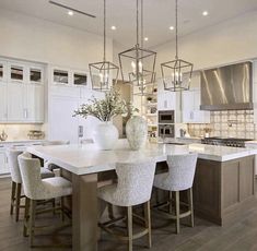 a large kitchen with white cabinets and marble counter tops, an island with four stools