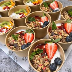 several bowls filled with granola and fruit sitting on top of a paper towel next to a cup of yogurt