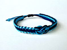 a blue and black rope bracelet with an elephant head charm on the end, sitting on a white surface