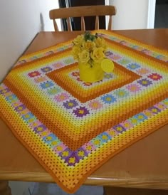 a crocheted tablecloth with flowers on it sitting on a dining room table