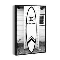 a black and white photo of a chanel surfboard hanging on a wall in front of a house