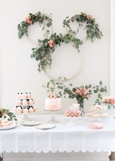 a table topped with cakes and desserts covered in greenery