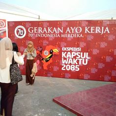 some people are standing in front of a red wall with an image of a bird on it