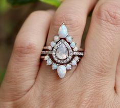 a woman's hand holding an opal and diamond ring