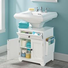 a white sink sitting under a mirror next to a bathroom vanity with blue towels on it