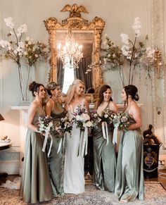 a group of women standing next to each other holding bouquets in front of a mirror