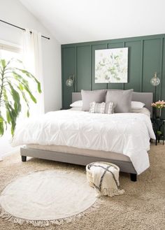 a bed with white sheets and pillows on top of it in a room that has green walls