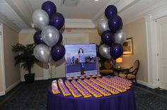 a table topped with purple and silver balloons next to a photo on top of it