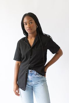 "Vintage black short sleeve shirt with great simple collar, 4 snap buttons, one front rounded patch pocket. Simple addition to any wardrobe and a great transitional piece. Maker: Military Made in the USA in the 60s. Garment Dyed in Los Angeles in 2019. Material: 100% Cotton. Condition: Two Options : Good with some small repairs that include darning. OR Small Holes and scuffs. Not perfect. Measurements: X- SMALL: Shoulder: 16\" | Chest: 17-18\" | Length: 27\" | Sleeve: 9.5\" SMALL: Shoulder: 17\" Washed Black Short Sleeve Tops With Pockets, Black Collared Camp Shirt With Pockets, Black Relaxed Fit Shirt With Button Closure, Black Cotton Camp Shirt With Pockets, Black Camp Shirt With Johnny Collar, Black Shirt With Placket In Relaxed Fit, Black Relaxed Fit Shirt With Buttons, Black Relaxed Fit Camp Shirt With Button Closure, Summer Washed Black Cotton Shirt