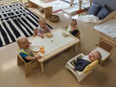 three babies sitting at a table eating food