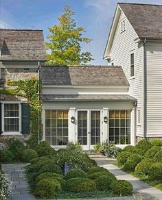 a white house with lots of windows and bushes