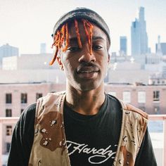 a man with dreadlocks on his head standing in front of a cityscape