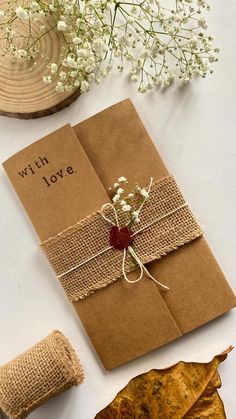 a brown envelope with a string tied to it sitting on top of a table next to some leaves