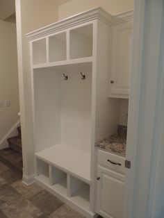 an empty room with white cabinets and marble counter tops