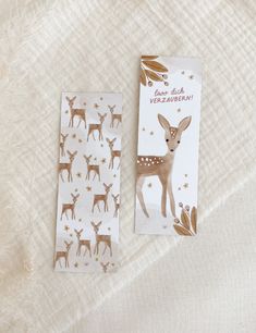 two deer stickers sitting next to each other on a white sheet with gold foil