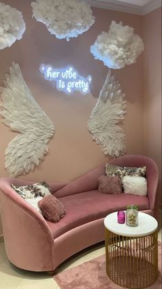 a living room with pink couches and angel wings on the wall