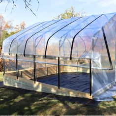 a small greenhouse in the middle of some grass