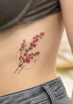 a close up of a woman's stomach with pink flowers on her side tattoo