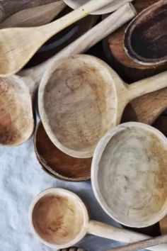 wooden spoons and bowls are lined up on a tablecloth with other wood utensils