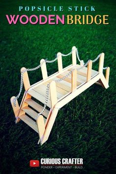 a wooden bridge with chains attached to it on the grass, and text reads popsicle stick wooden bridge curious crafter