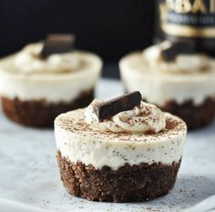 three cupcakes with white frosting and chocolate on top, one has a bite taken out of it