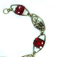 This is part of Chairish’s Costume Jewelry assortment.  1930s Art Deco 12k gold over sterling link bracelet. This delicate offering presents open elliptical links with smooth connectors, alternating heart-shaped leaves with emerald-cut ruby-colored  crystals. The workmanship is simple and meticulous, and the stones are vivid and evocative. Elegant and subtle, but with a hint of exuberance in the ruby crystals, this beauty is equally at home with a white shirt and jeans or a classic LBD. Not sign Vintage Charm Art Deco Jewelry For Formal Occasions, Art Deco Vintage Charm Jewelry For Formal Occasions, Formal Art Deco Jewelry With Vintage Charm, Elegant Vintage Charm Oval Link Jewelry, Elegant Jewelry With Vintage Charm And Oval Link, Rectangular Vintage Charm Jewelry For Formal Occasions, Red Art Deco Hallmarked Jewelry, Art Deco Ruby Jewelry For Formal Occasions, Vintage Oval Link Jewelry Gift