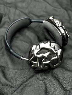 a pair of black and silver bracelets sitting on top of a leather covered surface