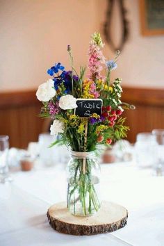 a vase filled with lots of flowers on top of a table covered in white linens