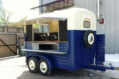 a blue and white food truck parked in front of a building with an awning