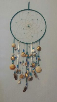 a wind chime with shells and beads hanging from it's side on the wall