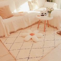 a living room filled with white furniture and flowers on the floor next to a window