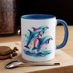 two dolphins jumping out of the water on a blue and white coffee mug next to a cookie