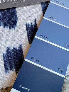 some blue and white paint swatches sitting on top of a bed next to each other