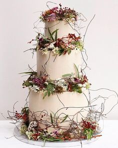 a three tiered cake with flowers and greenery on top