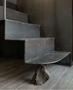 a cat is sitting on the floor in front of some stairs and an open door