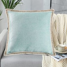 a light blue pillow sitting on top of a couch next to a potted plant