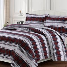 a red and black plaid bed in a room with white headboard, nightstands and windows