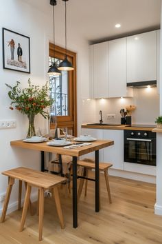 a kitchen with white cabinets and wood flooring next to a dining table set for two