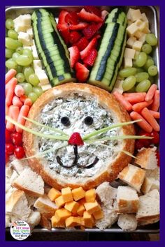 a metal tray filled with fruit and veggies next to a face made out of bread